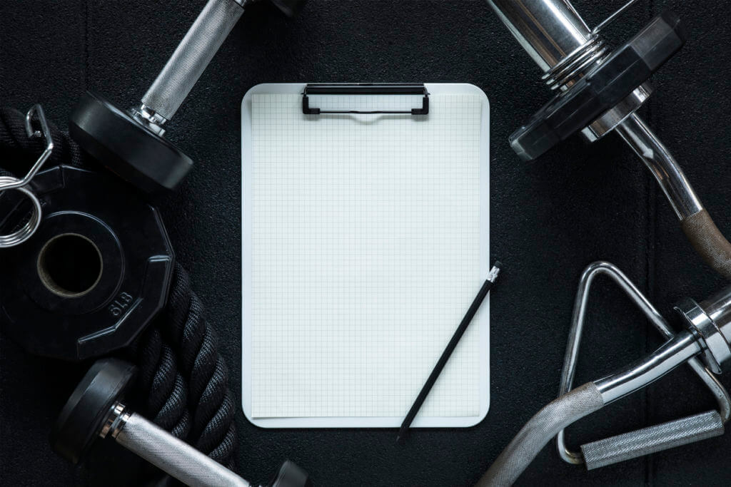 - Gym equipment with clipboard and pencil, illustrating the importance of tracking progress