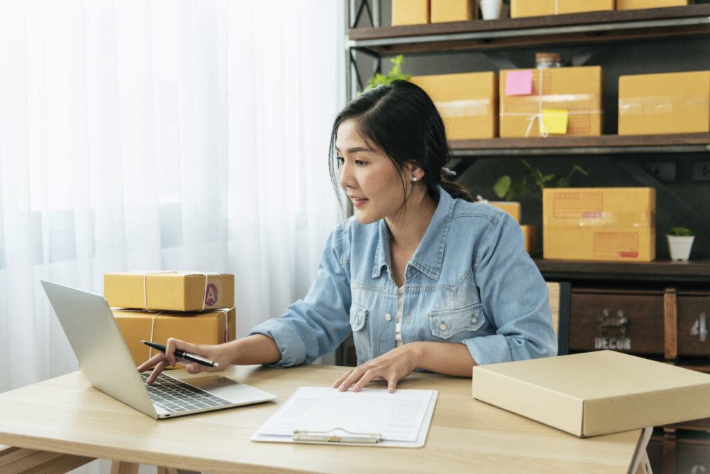 asian woman typing laptop keyboard checking online order, check goods stock delivery package shipping postal. Asian woman startup small business at home office