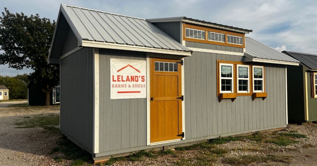- grey chalet shed with dormer and tan door