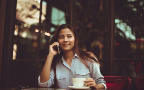 young woman sits outside her tiny house