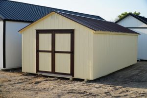 A white shed with a brown roof available for sale.