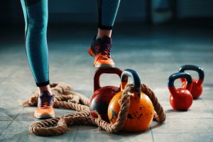 A woman is standing on a rope with kettlebells, showcasing her impressive balancing and strength abilities.