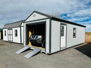 A car is parked next to a storage shed available for sale.