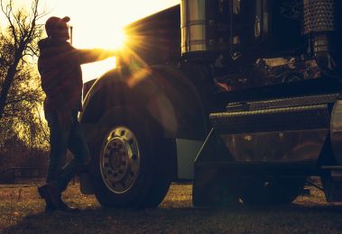 A man standing in front of a semi truck at sunset for sale.