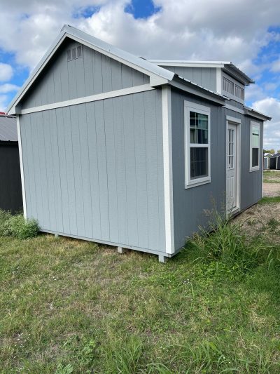 A small gray 12x20 Chalet Shed sitting in a grassy area, available for sheds on sale near me.