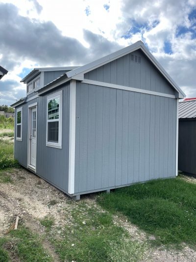 Two 12x20 Chalet Sheds for sale sitting in a grassy area.