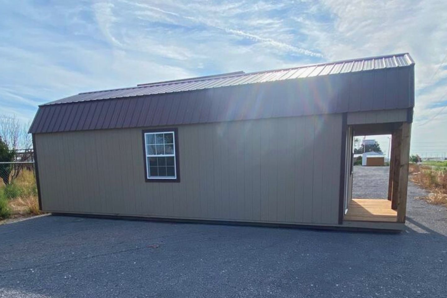 A 16x40 lofted barn shed with a brown metal roof sitting in a dealers lot.
