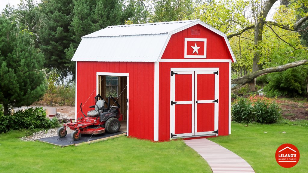 A red shed with a lawn mower in front of it.