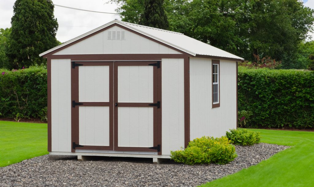 A white and brown shed sitting in a grassy area.