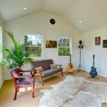 A living room with a guitar and a chair. - LELAND'S SHEDS - A living room with a guitar and a chair.