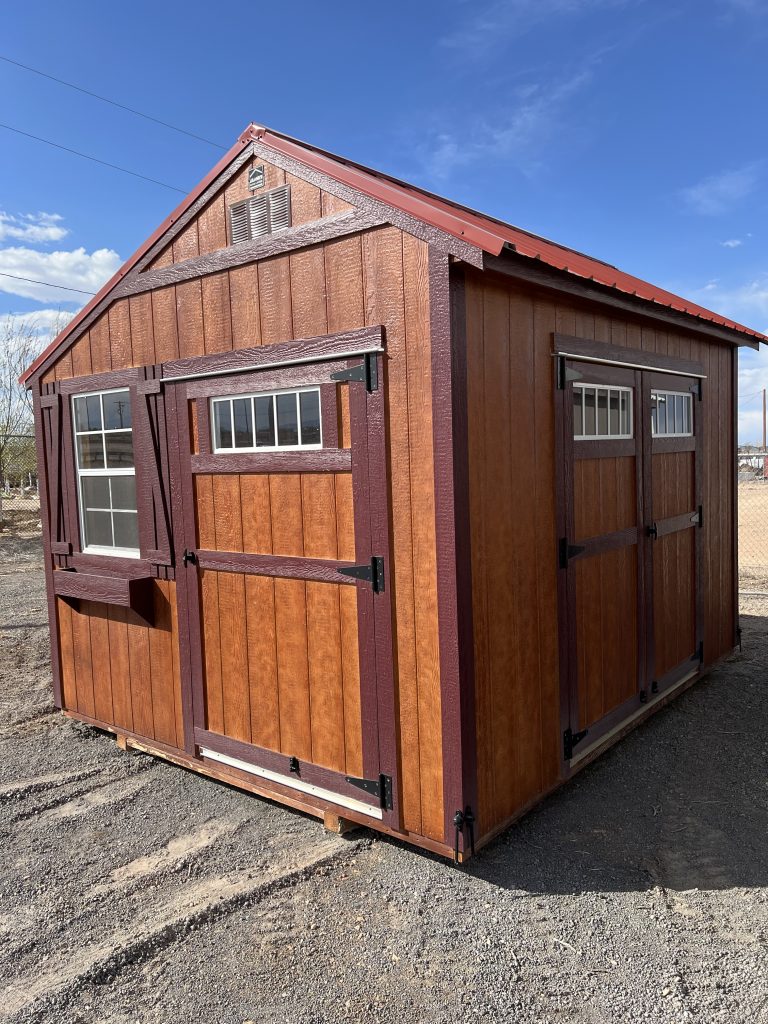  - Wooden shed with brown panels and purple trim, metal hinges, and small windows on a sunny day in a dirt lot