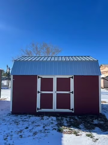  - Small shed with purple walls, white double doors, and a metal roof in a snowy yard under a clear blue sky.