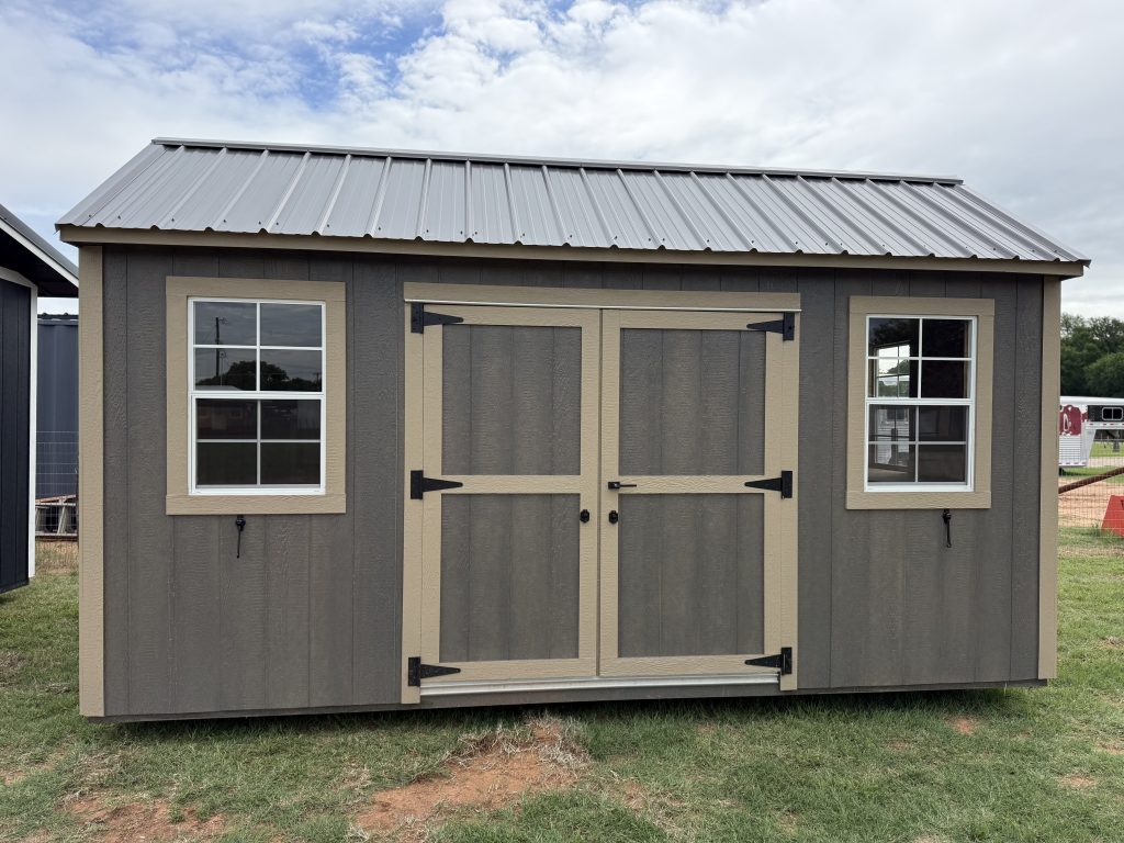  - Gray shed with beige trim and a metal standing-seam roof; two windows and a double door visible on the front side.