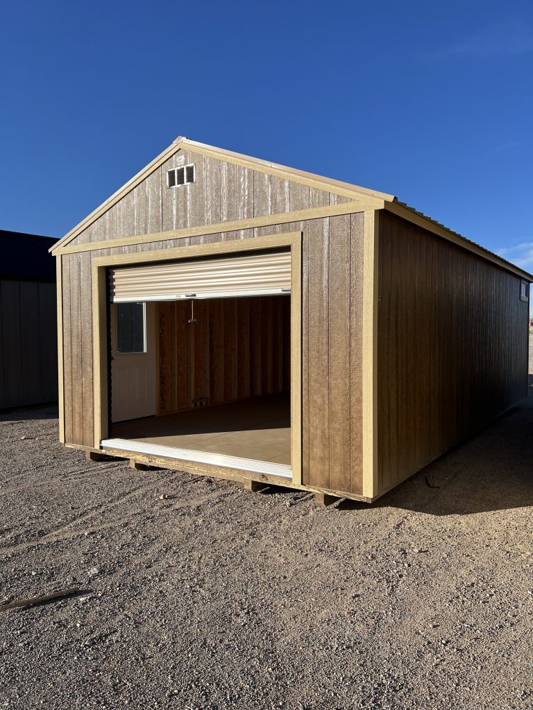  - Brown storage shed with vertical siding and a partially opened roll-up door, revealing an unfinished interior on a gravel lot under a clear blue sky.