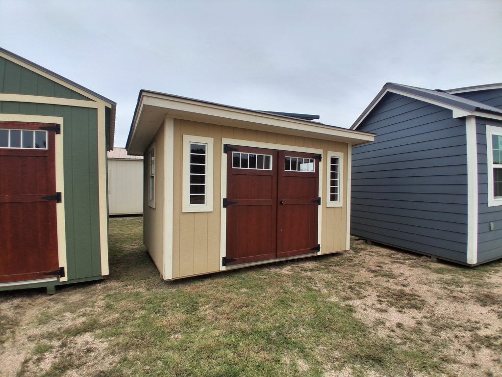 - - Row of small colorful sheds with brown doors and white-framed windows, lined up on grassy ground.