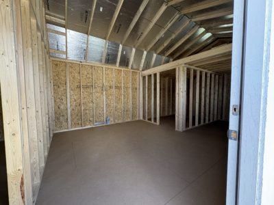 IMG_3857 - LELAND'S SHEDS - Unfinished interior with wooden studs, OSB walls, and a vaulted ceiling under construction in an attic space.