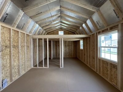 IMG_3859 - LELAND'S SHEDS - Interior of a new home under construction with exposed wooden framing, OSB walls, and a vaulted metal-roof ceiling.