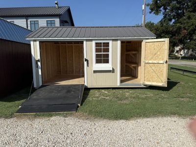 IMG_3865 - LELAND'S SHEDS - Outbuilding shed with a ramp and two open bays; left bay empty, right bay shows shelving.