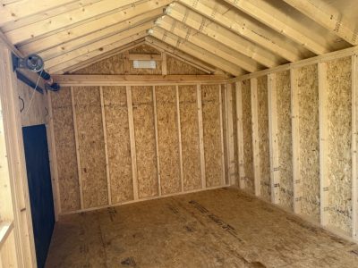 IMG_3867 - LELAND'S SHEDS - Interior of a small wooden storage shed under construction, with exposed framing, OSB walls, and a pitched roof.