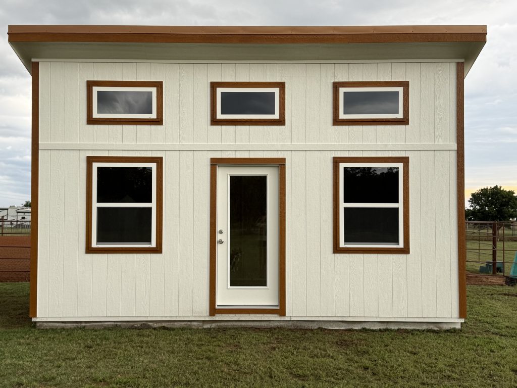 - - Beige prefab house with brown trim, two rows of windows: three small horizontal windows on the upper level and two large windows with a central glass door on the lower level.