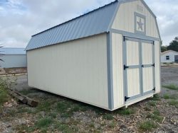 A 10x20 Lofted Barn Shed with a metal roof sitting on a gravel lot, available at sheds on sale.