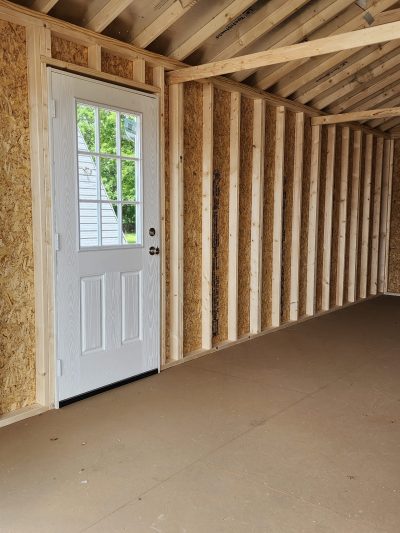 A 12x24 Garage Shed featuring wood walls and a sturdy door.