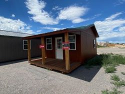Two 14x24 Cottage Sheds for sale in a parking lot.