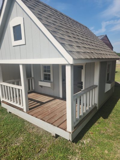 A cozy dog house with a porch and deck offering 8x10 Hideout Playhouse for sale nearby.
