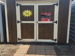 A 10x12 Utility Shed with a sign on it, available for sheds sale near me.