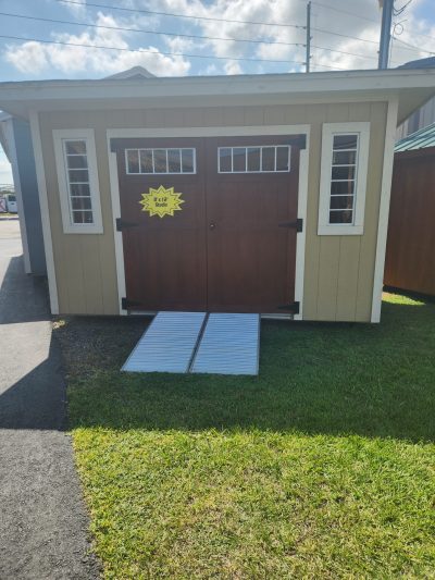 A for sale 8x12 Studio Shed with two doors and a sign on it.