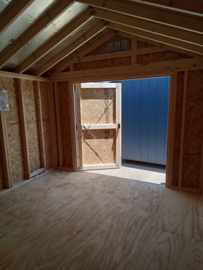 An open door reveals the interior of a 10x12 Utility Shed available for sale.