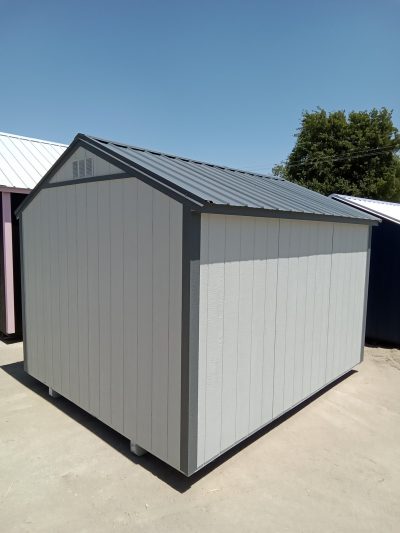 A 10x12 Utility Shed with a metal roof in a parking lot. For sale.