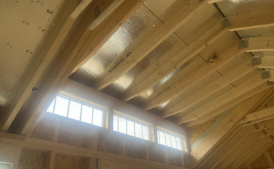 The ceiling of a 10x20 Chalet Shed adorned with beautiful wood beams and large windows.