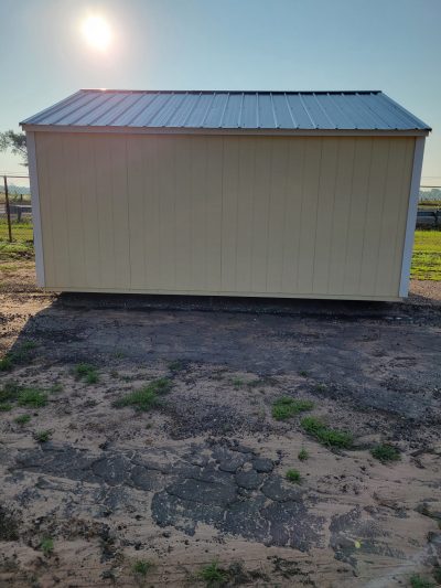 A yellow 10x16 Garden Shed with a metal roof for sale, situated in the middle of a field.
