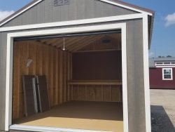 A 12x16 Garage Shed with an open door, available at a nearby shed store on sale.