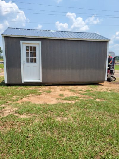 A 12x20 Garage Shed for sale with a door in the middle of a field.