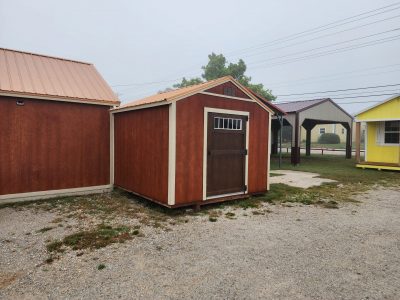Two 10x10 Utility Sheds for sale in a parking lot.