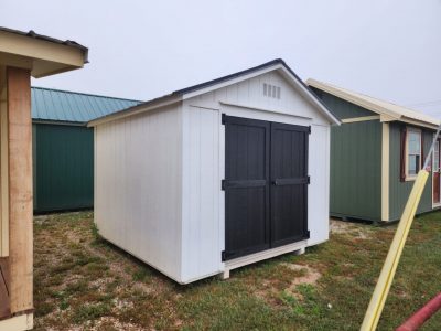 Two 10x10 Utility Sheds for sale in a yard next to each other.