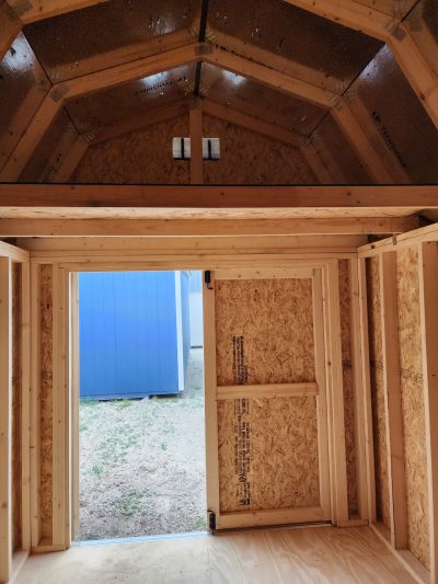For sale 8x12 Lofted Barn - The inside of a wooden shed with a door that is currently available for sale.