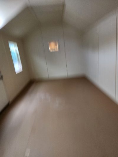 A blurry image of a 12x24 Diamond Chalet Shed with white walls.