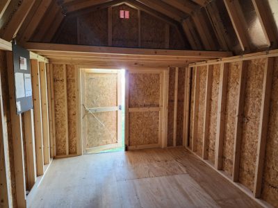 For sale: The inside of a 10x16 Lofted Barn with wooden walls and a door. Browse our shed store near me for great deals on 10x16 Lofted Barns. Don't miss out on our 10x16 Lofted Barns on sale!