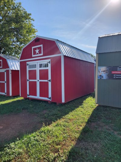 Two 10x16 Lofted Barns for sale next to each other in a field.
