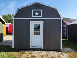 A gray and white 14x16 Lofted Barn with a star on it, available for sale at a nearby shed store.