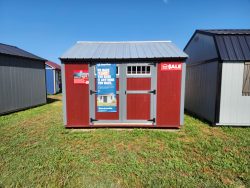 Two 12x12 Utility Sheds on sale in a field next to each other.