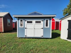 Two 8x12 Studio Sheds for sale in a field next to each other.