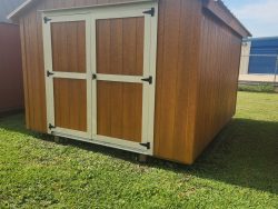For sale 10x12 Basic Shed sitting on a grassy field.