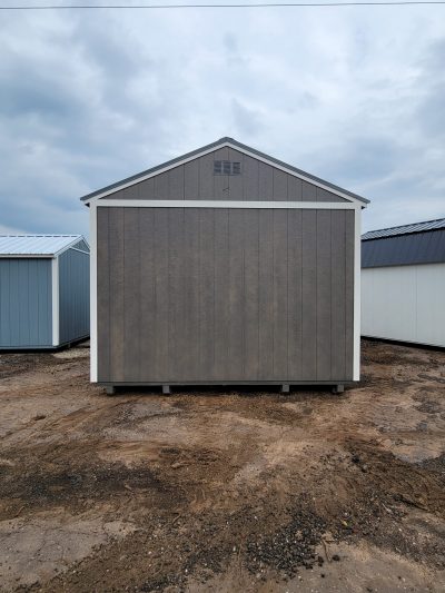 Two 12x20 Garage Sheds for sale in a dirt lot next to each other.