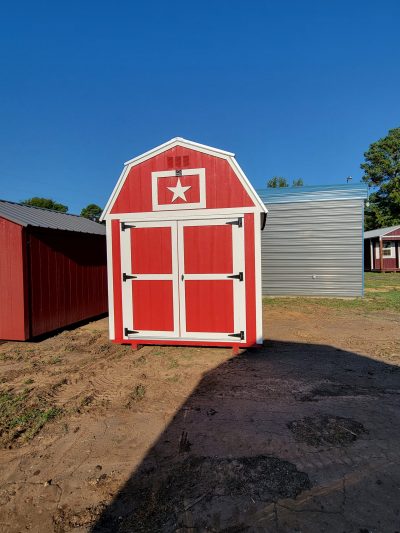 Two 8x12 Lofted Barn Sheds for sale in a dirt field.