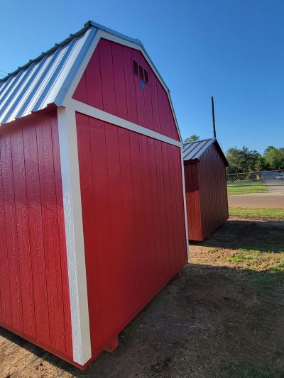 Two 8x12 Lofted Barn Sheds on sale next to each other in a field.