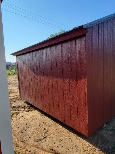 For sale: A vibrant red 10x12 Basic Shed nestled in a rustic dirt field. Experience the charm of this eye-catching structure while exploring sheds on sale nearby.